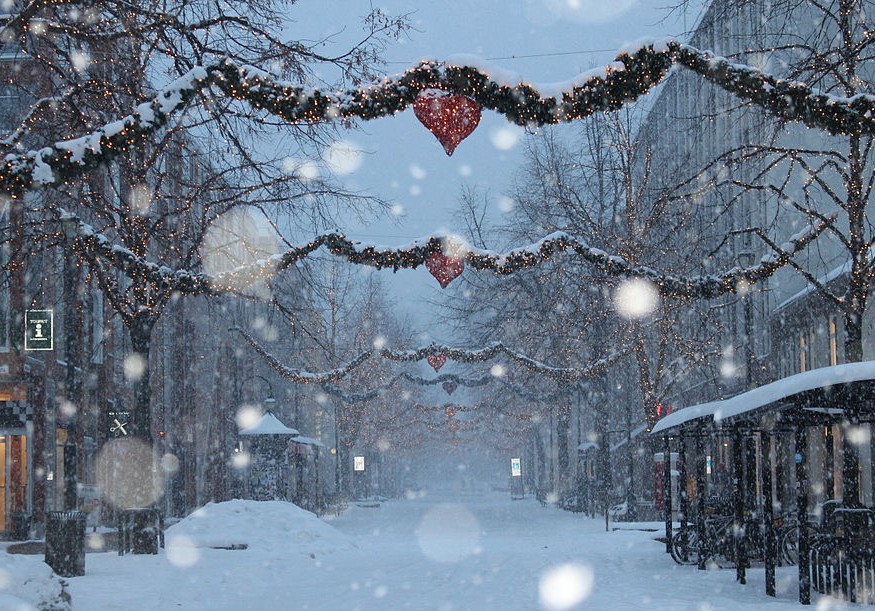 snow falling in a street decorated for christmas